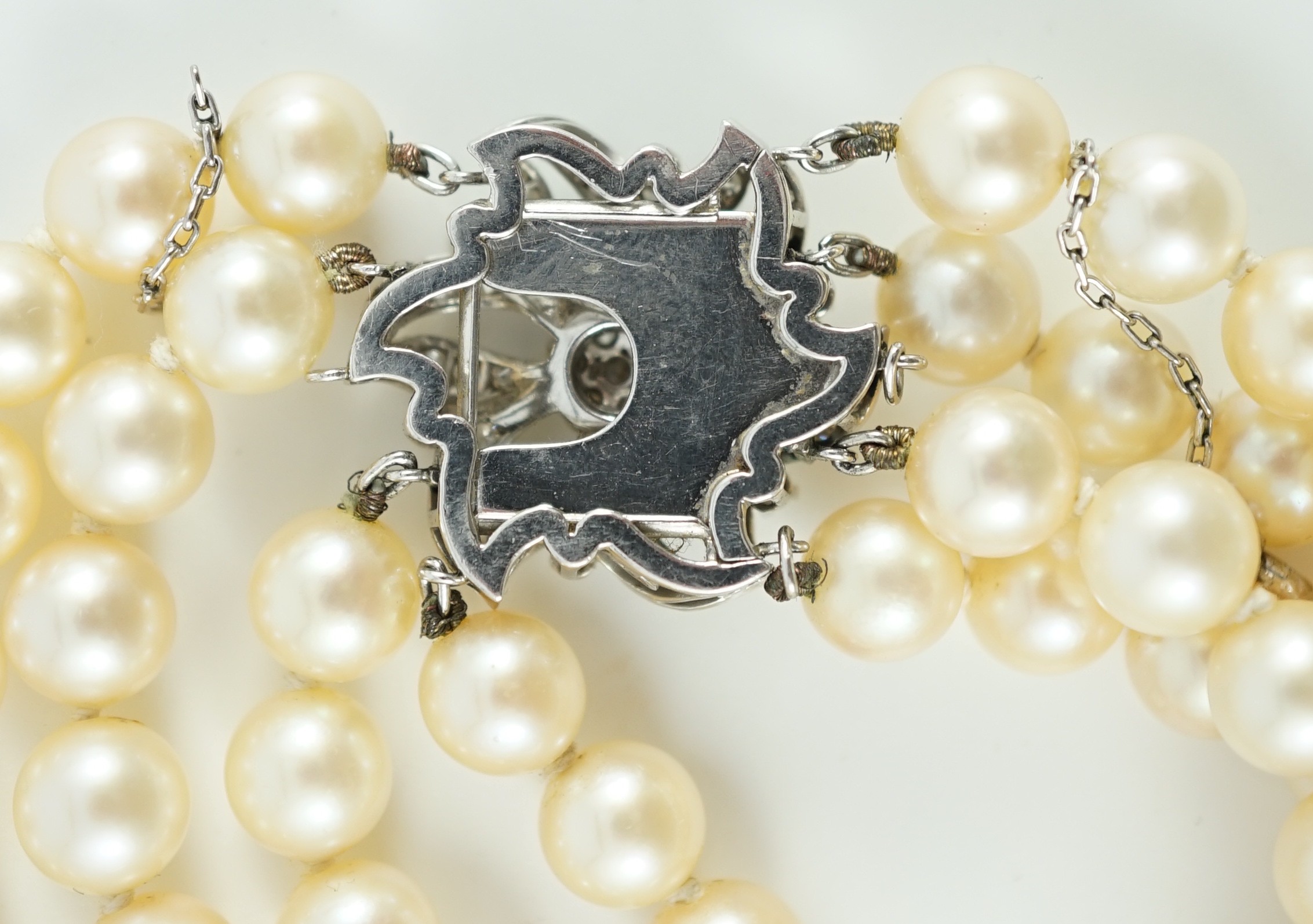 A mid to late 20th century continental quadruple strand cultured pearl necklace, with white gold and diamond cluster set flower head clasp